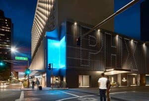 Urban building with illuminated signage for Aquatic Plant Management Society at night.